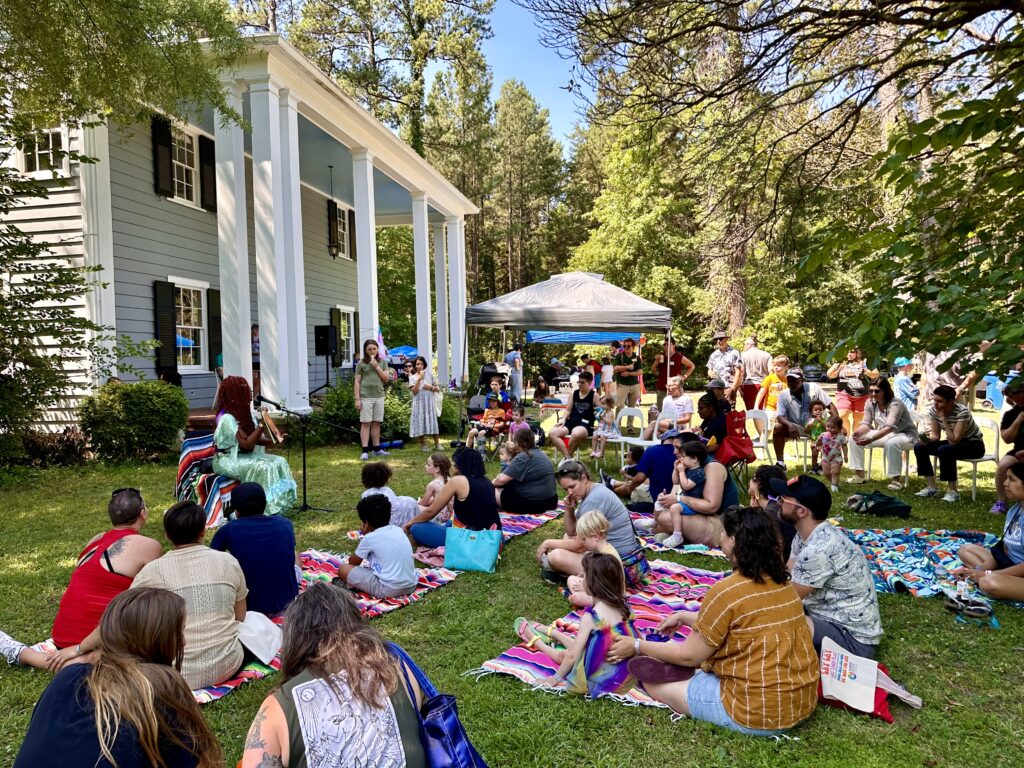 photo of drag storytelling event with families outside in front of large house