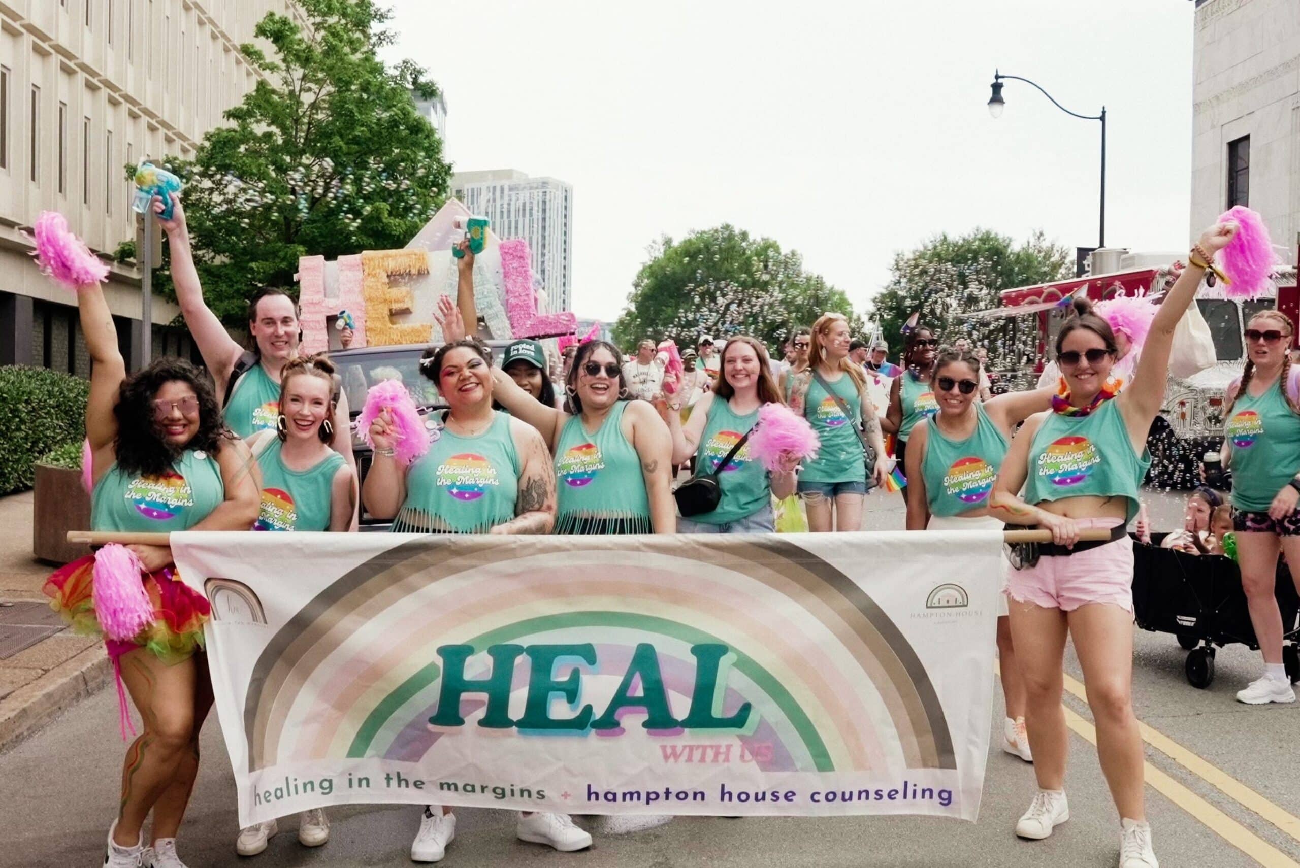 photo of healing in the margins marching in a parade with a banner